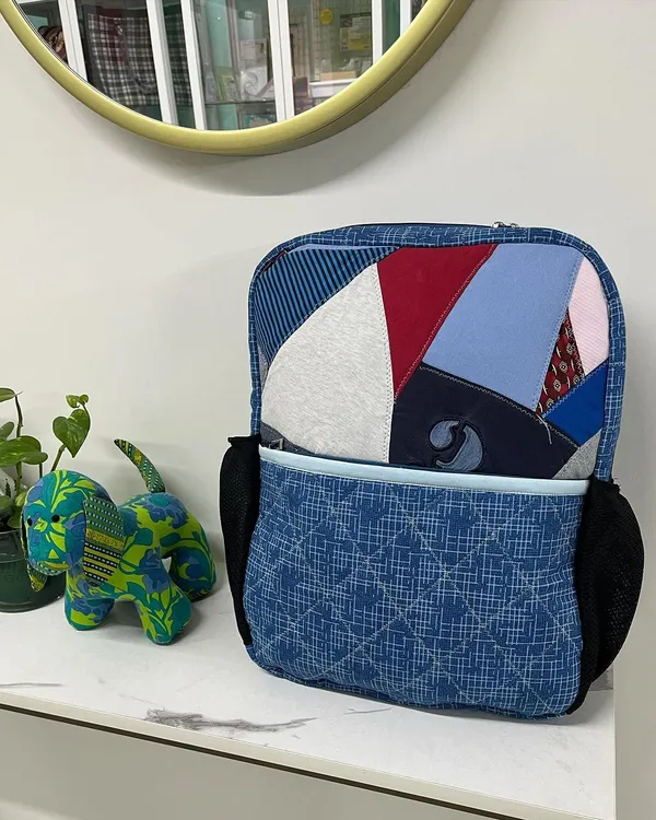A custom-made backpack created by upcycling a client's old T-shirts and shirts. This unique bag includes a laptop compartment and inner pockets, making it both personal and practical.