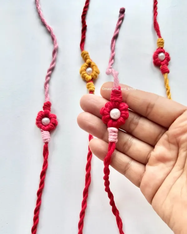 Holding one of my handmade floral Rakhis. I designed these for Rakshabandhan, featuring a delicate flower knot with a pearl bead in the center and twisted ties.