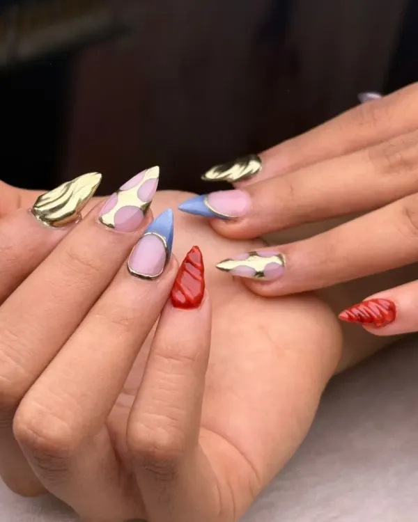 A playful and eclectic set that showcases a variety of techniques. It features gold chrome, cow print, textured red, and sheer blue nails for a fun, mismatched look that is full of personality.