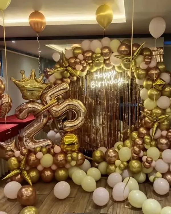 This lavish 25th birthday celebration in Bangalore shows how we can transform a space. The setup features a full backdrop with a custom neon sign, and an organic arch of chrome gold, rose gold, and white balloons, complete with a large number 25 and a crown foil.