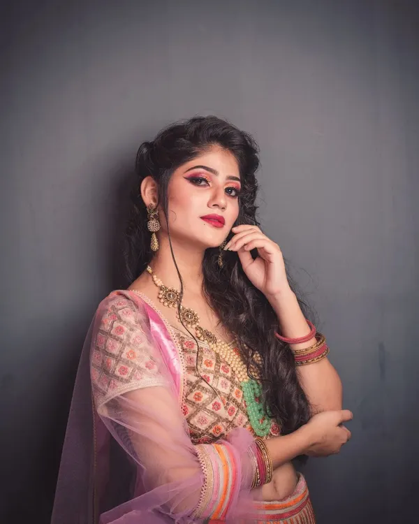 A fashion portrait with a confident attitude. I used a simple grey background and soft lighting to put all the focus on the model's expressive look, her vibrant makeup, and the intricate details of her pastel lehenga.