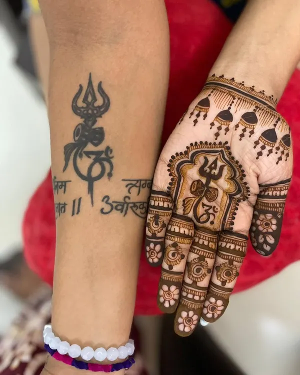 For the devotee, a design that keeps Mahadev close. This special mehendi incorporates the Trishul and Om symbols, designed to sit alongside the client's existing tattoo, creating a powerful and personal statement of faith.