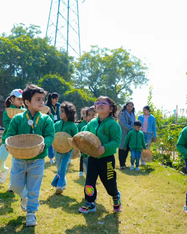 A group of young students in matching green jackets, excitedly carrying their baskets for a vegetable harvesting activity.