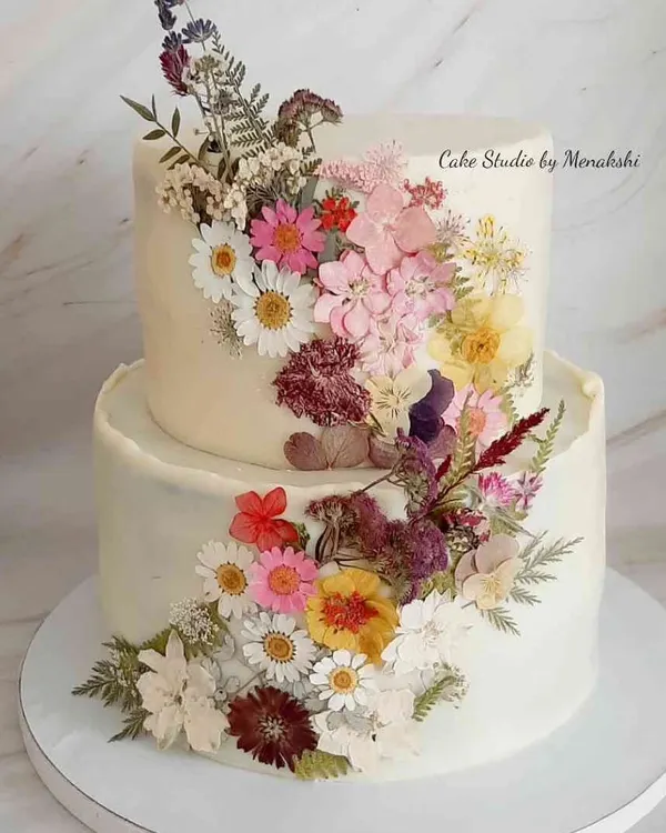This two-tier wedding cake is one of my proudest creations, adorned with a cascade of real, hand-pressed dried flowers. It’s a perfect example of how we can use natural elements to create something truly breathtaking for your special day, all with a smooth buttercream finish.