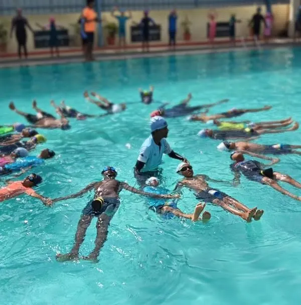 Our instructor guides the class through various poses during an International Yoga Day event. The group holds hands, creating a circle of shared energy and focus in the water.