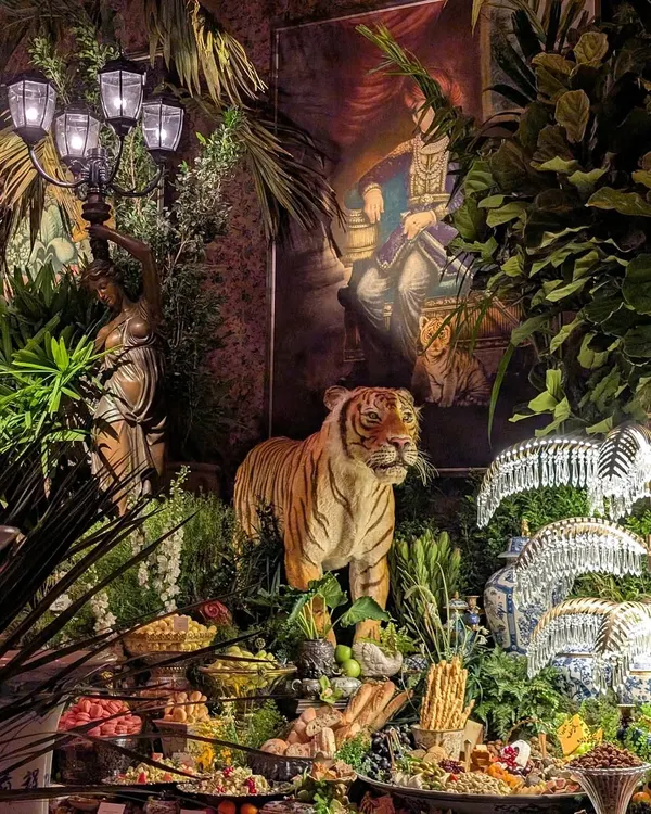 The decor for the Sabyasachi 25th anniversary was all about opulence and grandeur. This shot shows how we integrated lush greenery around the event's props, like this tiger statue and ornate lamps, to create a scene that felt like a royal jungle.