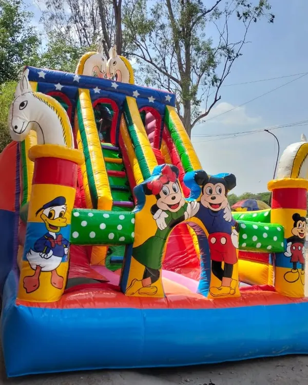 Here is a classic Mickey and Friends bouncy slide. It has Mickey, Minnie, and Donald Duck, with fun horse figures on the side. The bright colors make it a cheerful centerpiece for any birthday party.