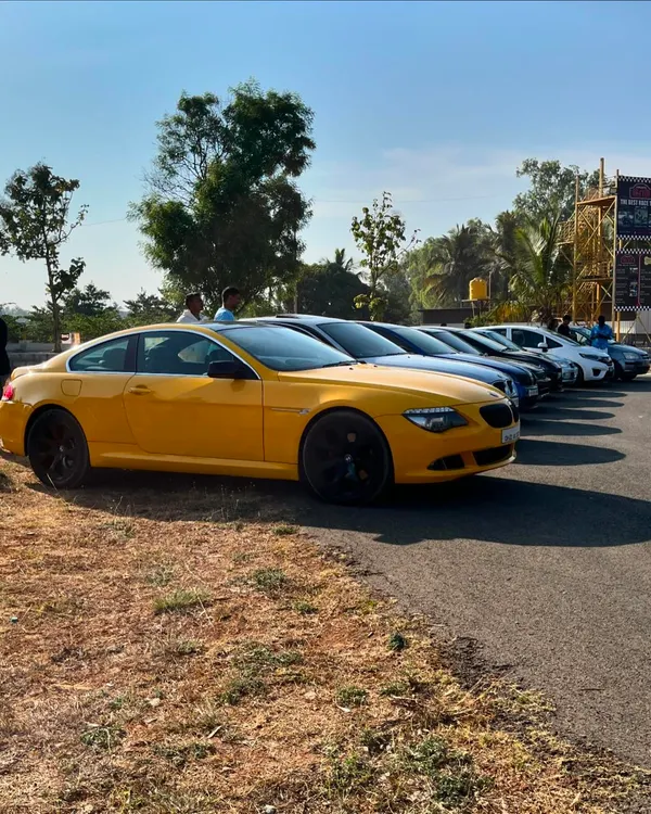 A lineup of high-performance cars, including a bright yellow BMW, at a Cars & Coffee meet. This is the kind of quality and passion you'll find at our community events.