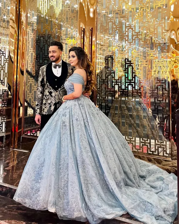 A happy client and her partner at their engagement. She is wearing my popular powder blue off-shoulder ball gown, which features delicate embroidery and a flowing train that looks stunning in photos.