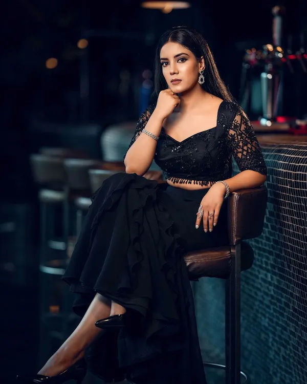 This is our hero shot. A model poses in a modern black lehenga at a bar, capturing a bold, editorial mood perfect for a designer lookbook or social media campaign. The dramatic lighting and confident pose tell a story of contemporary elegance.