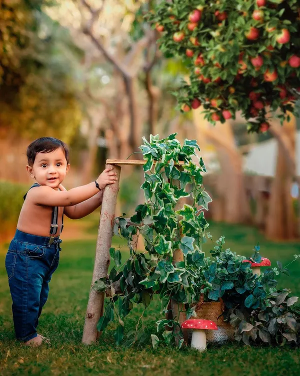 A charming outdoor portrait of a toddler during a golden hour session. The rustic props like the ladder and apple tree create a storybook feel for this sitter session.
