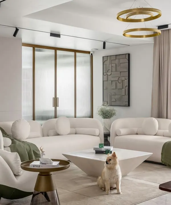 In this contemporary living room, we paired plush off-white sofas with dual-tone armchairs to create a cozy yet elegant seating arrangement. The space is grounded by a geometric coffee table and accented with touches of green and bronze, reflecting a harmonious and minimalist design.