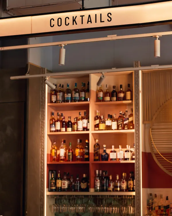 The view from behind our bar, fully stocked with a world-class selection of spirits. The 'Cocktails' sign says it all: this is where the magic happens. We can create a custom bar menu for your event.