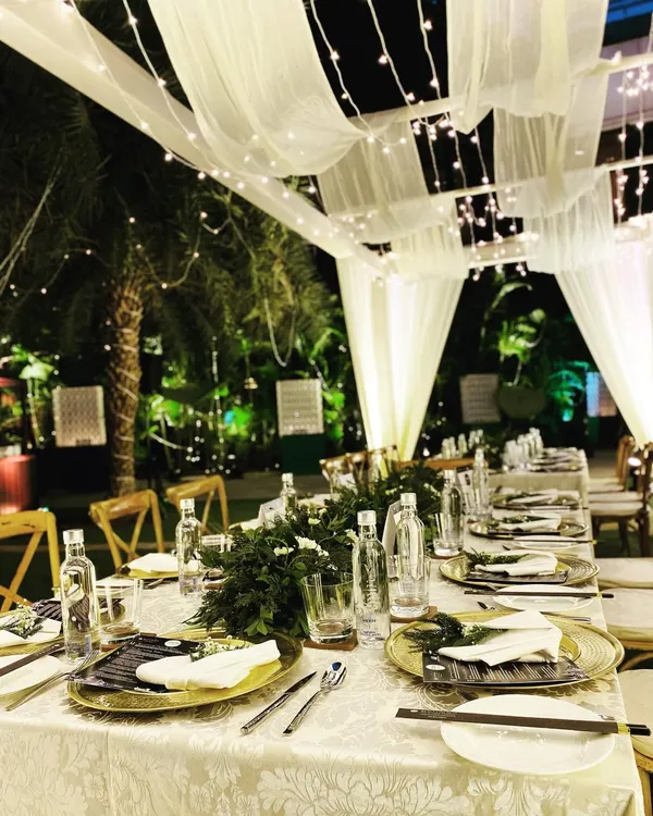 An intimate sit-down dinner setup in the courtyard of the Pullman New Delhi. The decor features a canopy of white drapes and fairy lights, creating a magical, starlit ambiance for a special evening.