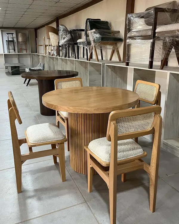 A beautiful four-seater dining set featuring a round table with a fluted base and matching chairs with cane backrests. This set is crafted from light-colored solid wood.