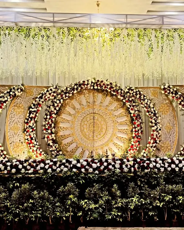 This is one of my most elaborate stage designs, featuring large carved panels in a gold and white theme. The multiple floral arches and dense greenery at the base give it a very grand and royal look, perfect for a large reception.