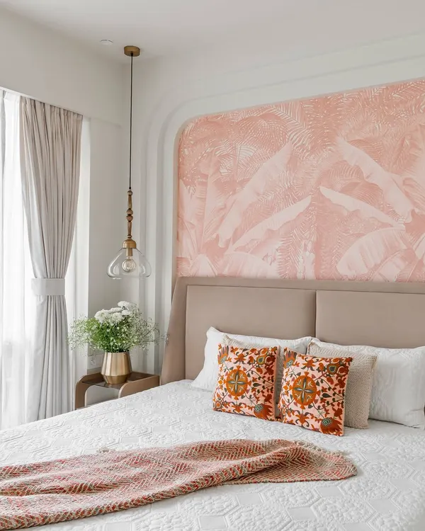 A tranquil bedroom from 'Project Lily,' featuring a custom bed with a beige upholstered headboard. The focal point is the arched niche with a delicate pink tropical wallpaper, creating a soft and dreamy ambiance.
