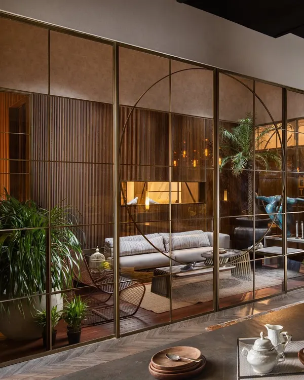 This floor-to-ceiling glass partition, framed with custom metal profiles, is designed to create distinct living and dining areas while maintaining a sense of light and openness. The integrated sliding doors allow for a seamless transition between spaces, embodying modern, flexible living.