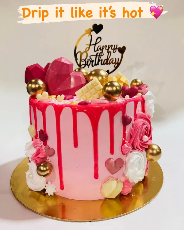 This vibrant pink drip cake is a party in itself. It's loaded with geometric chocolate hearts, white chocolate bars, and shiny golden spheres for a fun and luxurious birthday celebration.