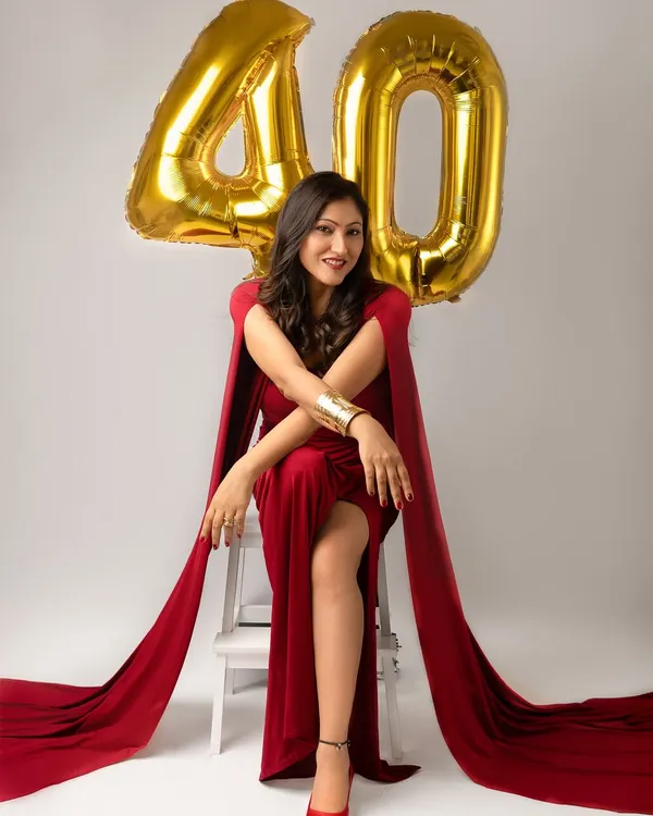 Turning forty is a power move, and this portrait is all about celebrating it. Dressed in a stunning red gown with cape sleeves, she looks absolutely radiant and ready to conquer her next decade.