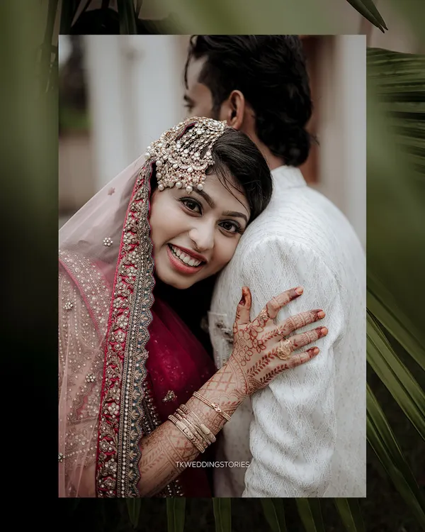 A warm and joyful portrait of a Muslim bride in a stunning red and gold outfit, embracing her groom. Her happy smile and the intricate henna are beautifully captured.