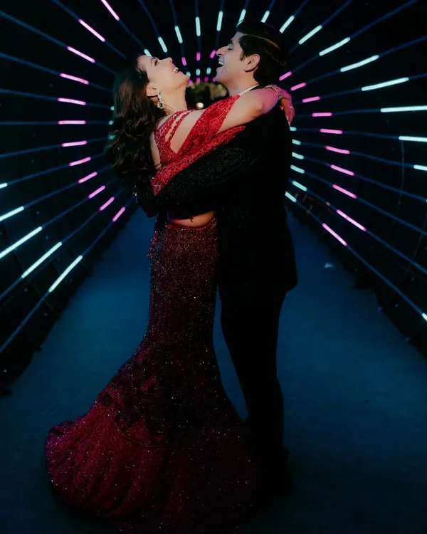 A couple shares a joyful, romantic moment inside a tunnel of neon lights. This shot from a Sangeet or Cocktail night showcases our ability to use creative lighting to capture modern, dynamic portraits.