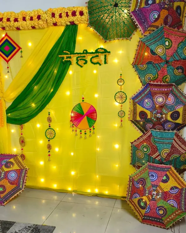 As the hero item, this is the first thing everyone sees. I designed this vibrant Mehndi backdrop to turn a simple room into a festive photo spot. The setup features bright yellow and green drapes lit with fairy lights, traditional Rajasthani umbrellas for a pop of color, and a custom 'Mehndi' sign to complete the look for the pre-wedding function.
