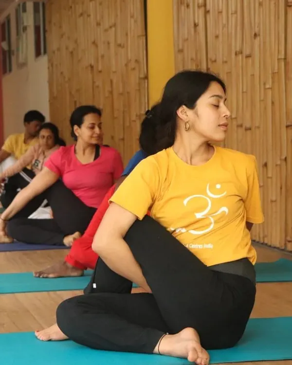 A student practices Ardha Matsyendrasana (Half Spinal Twist) during a group class. This posture energizes the spine, stimulates the liver and kidneys, and improves digestion.