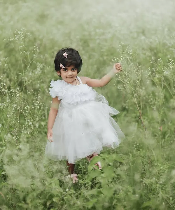 A little angel in a field of dreams. This toddler in a white dress looks so serene and beautiful surrounded by the soft greenery of nature.