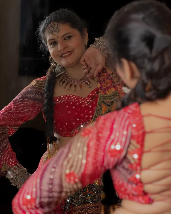 Getting ready for Navratri in a bespoke Garba outfit. This mirror-work blouse and colorful lehenga are designed for dancing the night away.