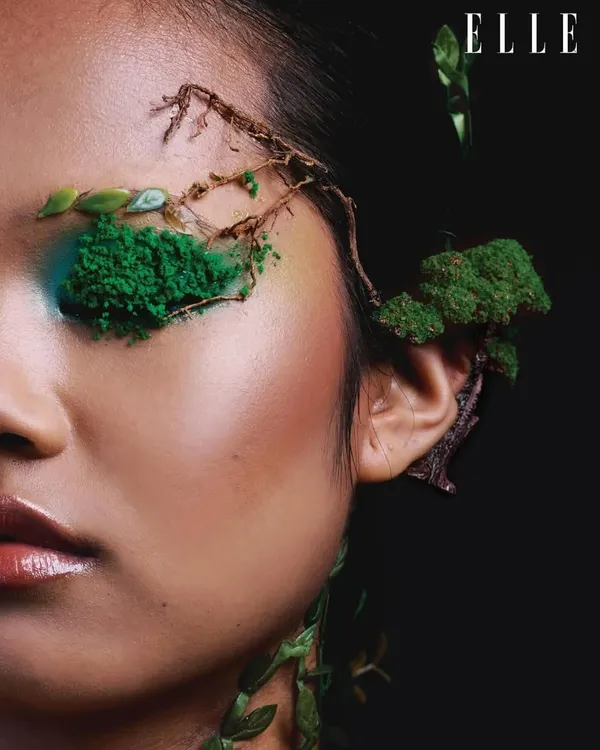 A close-up from the Elle India 'Becoming Earth' editorial, focusing on the intricate makeup detail. The use of moss, twigs, and textured green pigment transforms the face into a natural landscape.