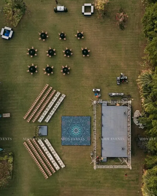 A 360-degree aerial view of a complete event setup. This shot showcases our precision in planning, with distinct zones for the stage, dance floor, lounge seating, and dining canopies all arranged perfectly.