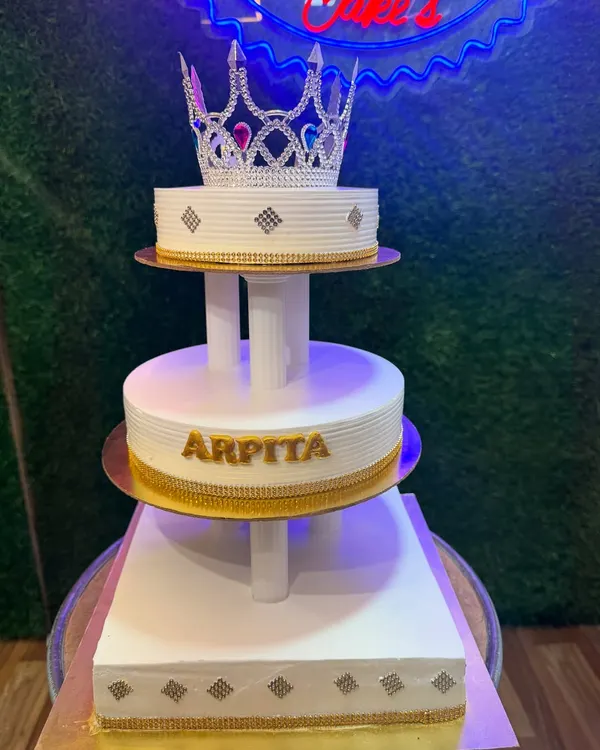 This magnificent three-tier cake with a sparkling crown topper is fit for royalty. The clean white design with gold accents creates a look of pure elegance, perfect for a grand birthday or wedding celebration.