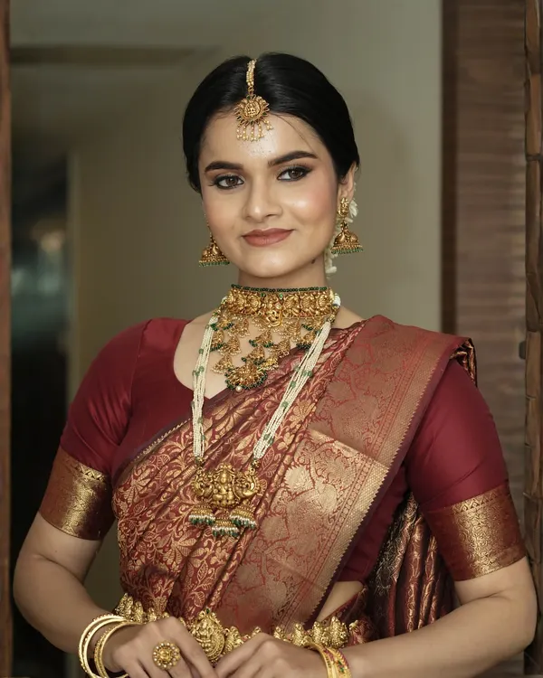 This is the quintessential South Indian bridal look I adore creating. It features flawless, glowing skin, elegantly defined eyes, and a soft matte lip, all coming together to complement the rich texture of the Kanjivaram saree and the intricate details of the temple jewellery.