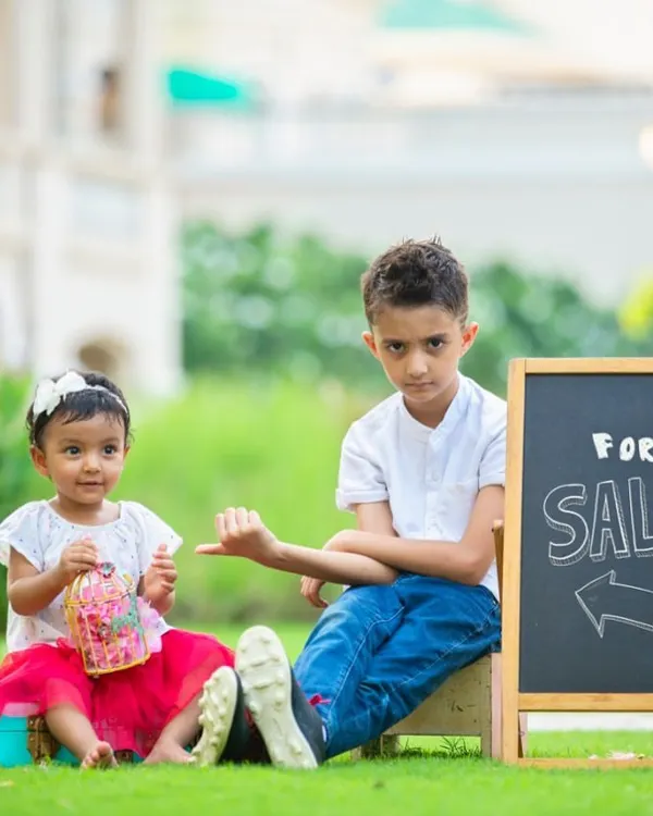 A perfect example of sibling humor. This big brother's playful pose and the funny sign add so much personality to this outdoor portrait with his little sister.