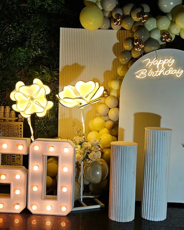 Celebrating a 50th birthday calls for something special and elegant. This setup features a classy white and gold theme with marquee numbers, a custom neon sign, and soft lighting to create a sophisticated atmosphere.