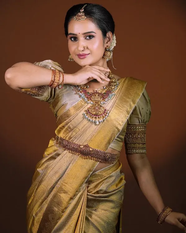 A polished and regal bridal portrait. This look features a stunning golden silk saree, complemented by temple jewelry and makeup that highlights the bride's natural elegance.