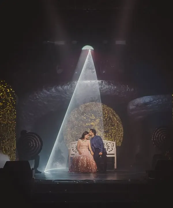 A quiet moment for the couple on a stage designed to feel like another dimension. A single beam of light creates an intimate, cinematic spotlight amidst the grand 'Interstellar' themed Sangeet.
