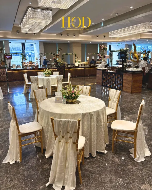 An elegant round table dining setup with beautifully draped chairs and a simple floral centerpiece, perfect for a sophisticated wedding reception.
