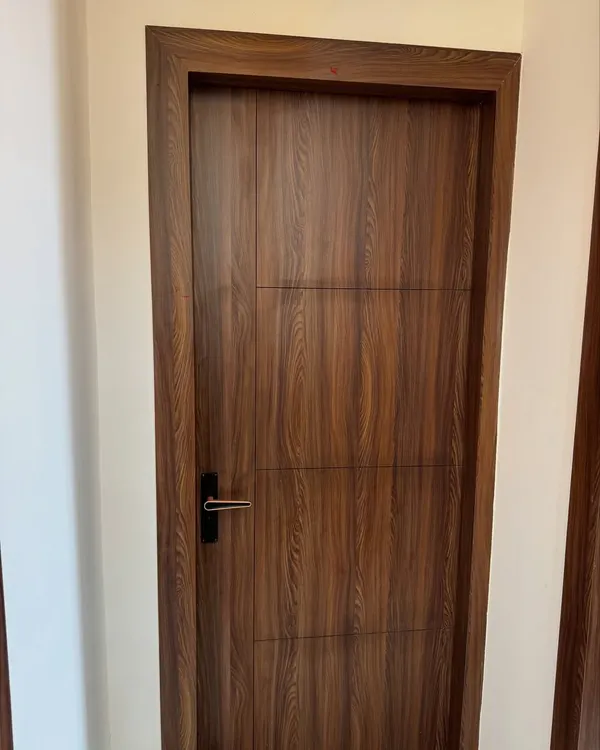 A modern flush door with a rich wood veneer and simple horizontal grooves, paired with a sleek black handle.