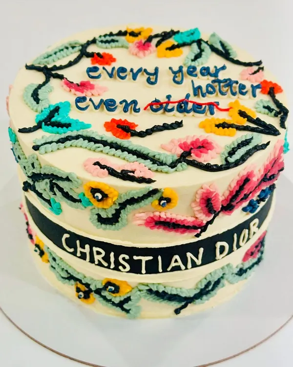 We were so excited to create this couture-inspired cake. The design features vibrant, intricate floral work piped with our signature vanilla buttercream, wrapped with an iconic brand ribbon. This decadent chocolate cake with a dark chocolate ganache filling is a perfect example of how we turn your high-fashion dreams into edible art.