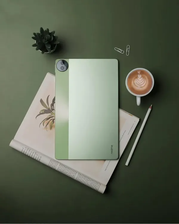 A top-down flatlay of the realme Pad 2, styled with a coffee cup, a notebook, and a plant to create a productive and creative workspace vibe.