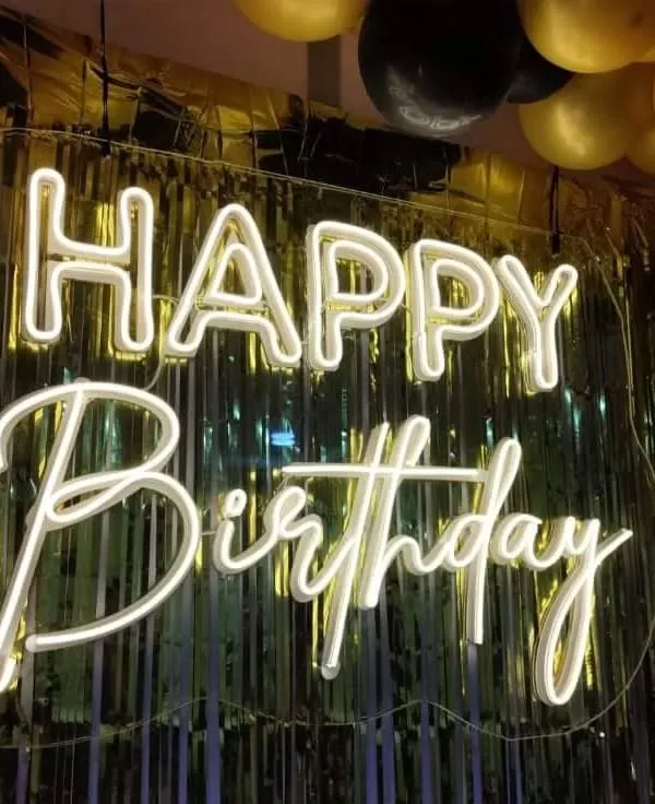 Our 'Happy Birthday' neon sign is one of our most popular rental items. It instantly brightens up any backdrop, like this golden foil curtain, and sets a festive mood.