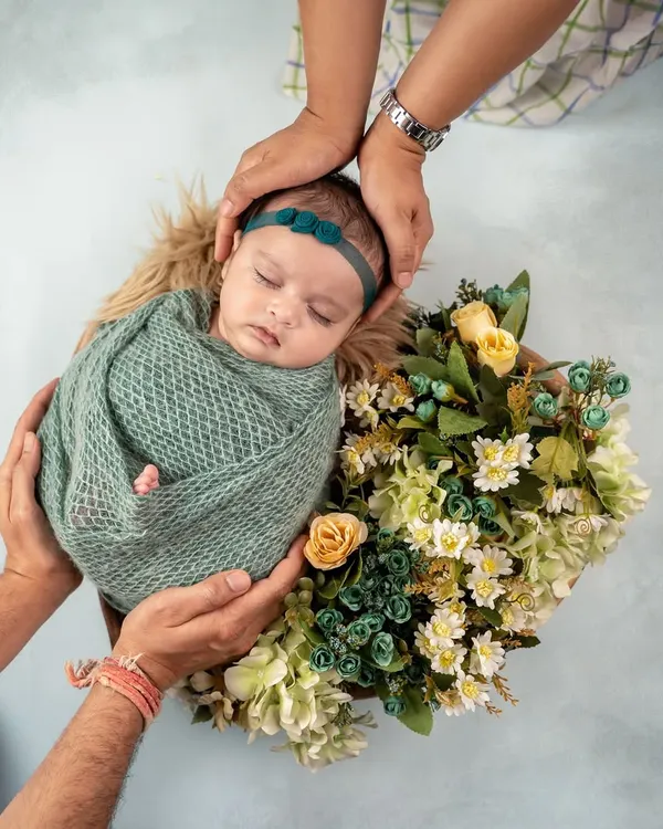 This is the moment I strive to capture: your beautiful baby, sleeping peacefully, held safely in your loving hands. This portrait combines a delicate floral theme with the profound connection of family.