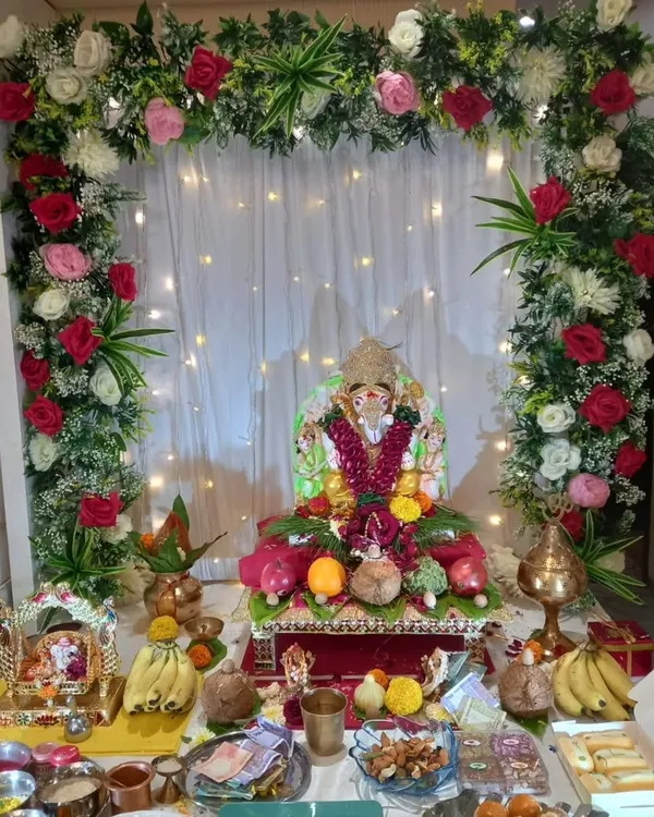 This is a full view of a home Ganpati setup, showing how our floral arch frames the idol and the entire puja area. The mix of red, pink, and white roses with green foliage creates a vibrant and celebratory atmosphere.