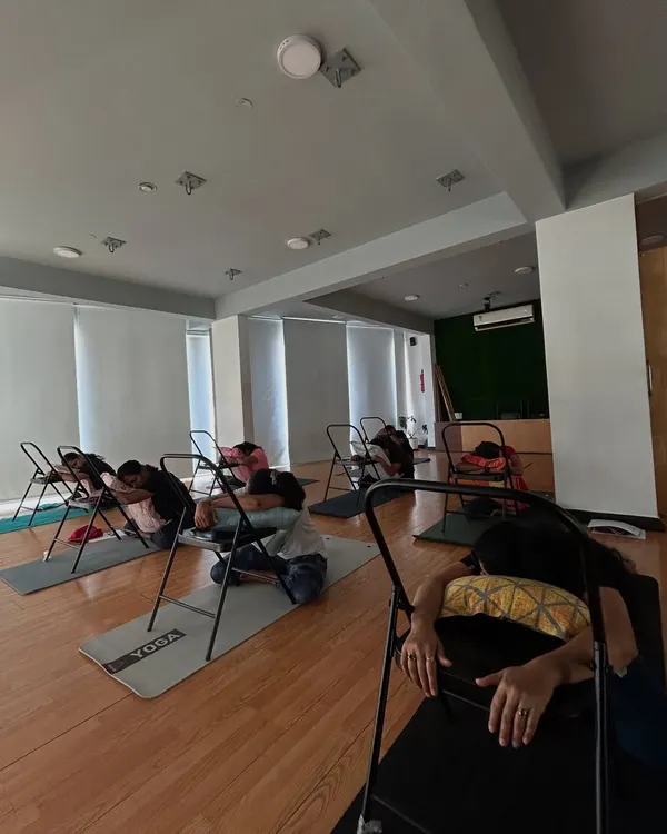 Members in our PCOD/PCOS workshop use chairs for a supported forward fold, a pose that helps calm the nervous system.