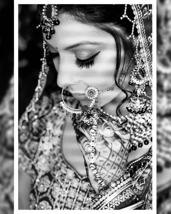 A black and white bridal portrait that emphasizes emotion and detail. This close-up focuses on the bride's intricate nath and henna, creating a classic, artistic photograph that feels timeless.