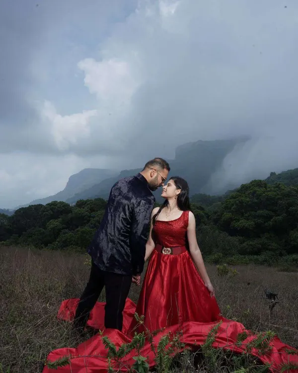 An intimate moment from a pre-wedding shoot against a stunning mountain backdrop. The makeup was designed to stand out yet look natural in the dramatic, cloudy lighting, pairing perfectly with her bold red gown.
