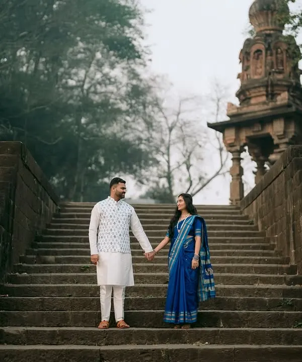 Hand in hand, Ankush and Aishwarya ascend the ancient stone steps at Sangam Mahuli. This wide shot captures the scale of the historic temple, making their journey together feel epic and significant.