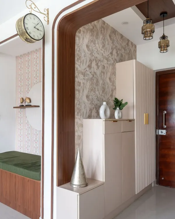 The foyer of 'The Flux Abode' features a mix of textures and shapes, with fluted cabinets, curved wooden frames, and a vintage-style clock.